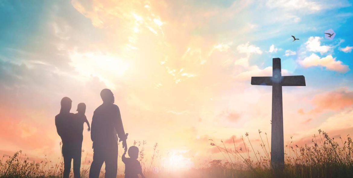 Silhouette father mother and two son looking for the cross on autumn sunrise background